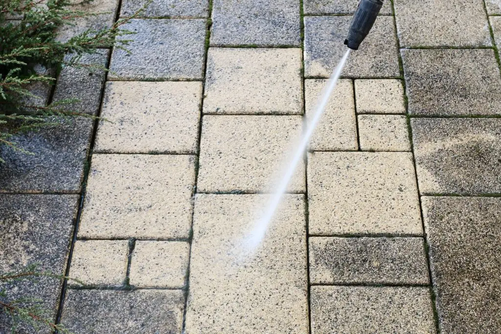 Cleaning dirty paving stones in the garden with a pressure washer. - Packard Power Washing patio cleaning